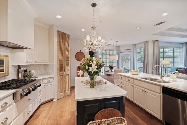 Kitchen after — white cabinetry, marble island, crystal chandelier, and open-plan living with dark accent wall