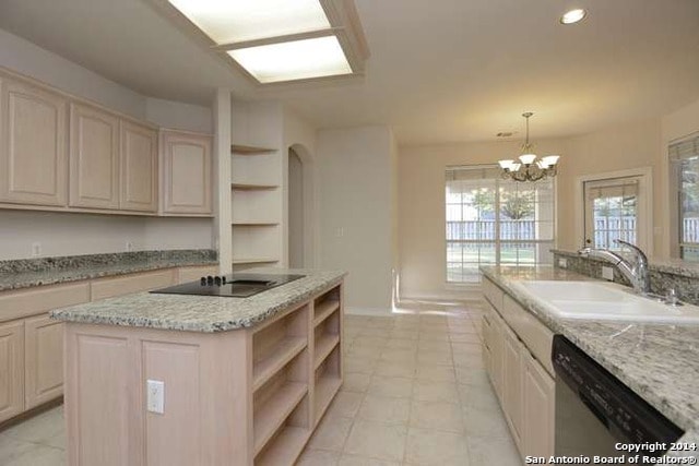 Kitchen before — dated tile floors, light maple cabinets, and open shelving