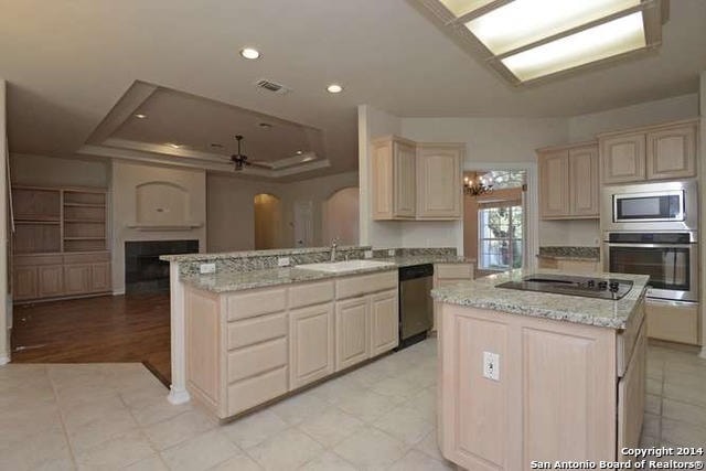 Kitchen before — builder-grade layout with light cabinets and tile floors
