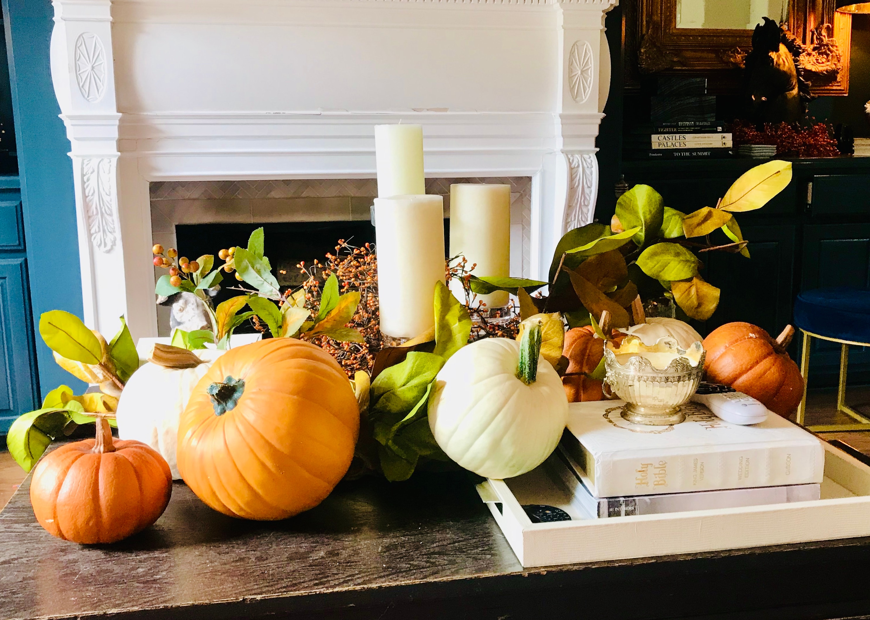 Autumn fireplace styling with pumpkins, candles, and greenery on a dark wood coffee table