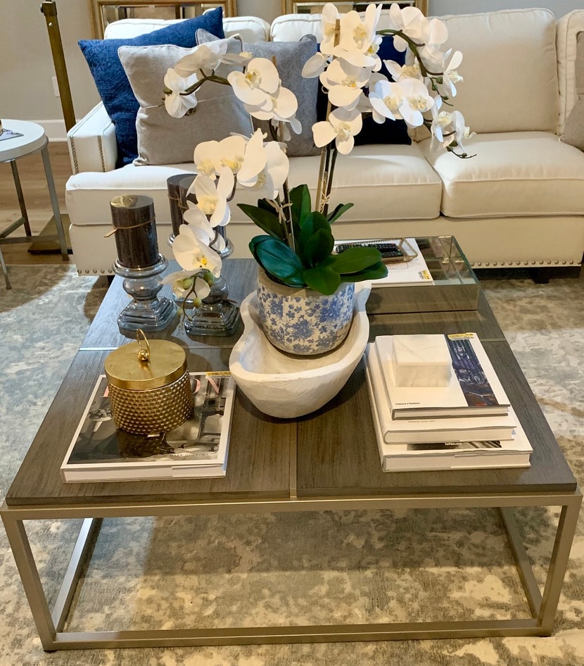 Styled coffee table with orchid, gold accents, and blue and white ceramic pot