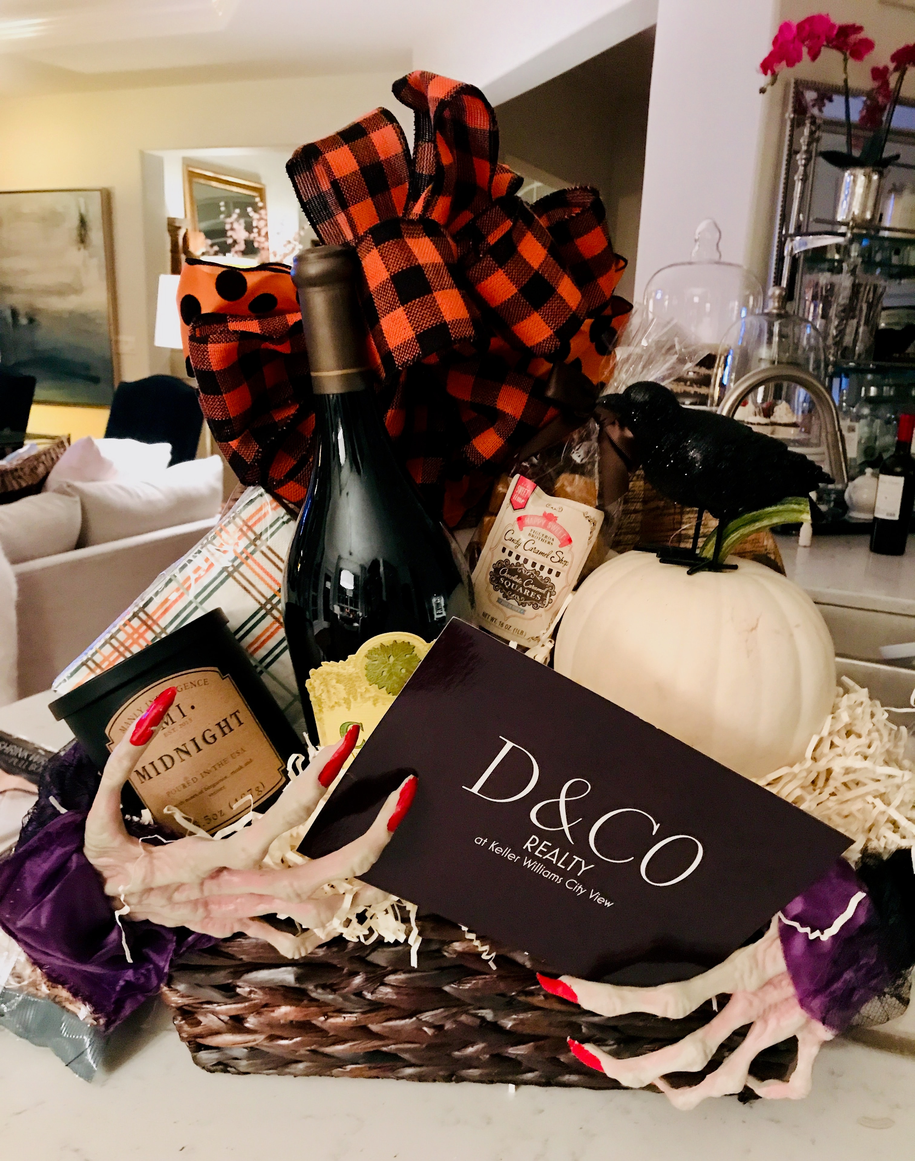 Halloween-themed D&CO Realty gift basket with wine, candles, and seasonal décor
