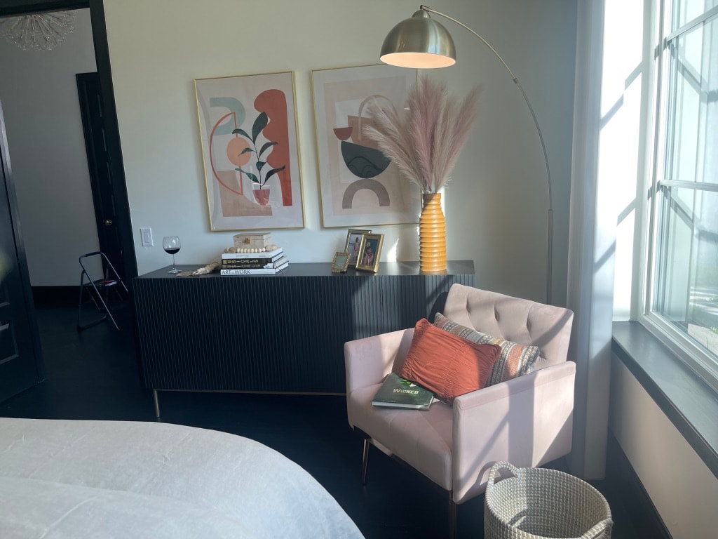 Modern bedroom sitting area with pink velvet chair, arc lamp, and abstract art