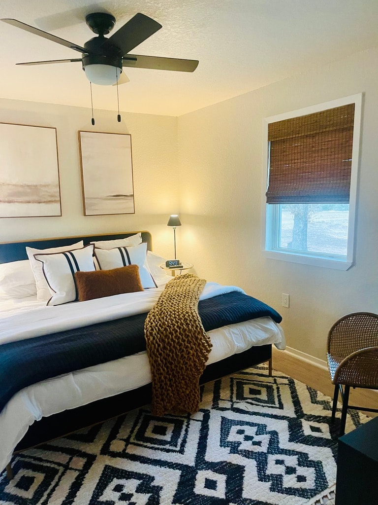 Navy and cream bedroom with geometric rug and bamboo roman shade